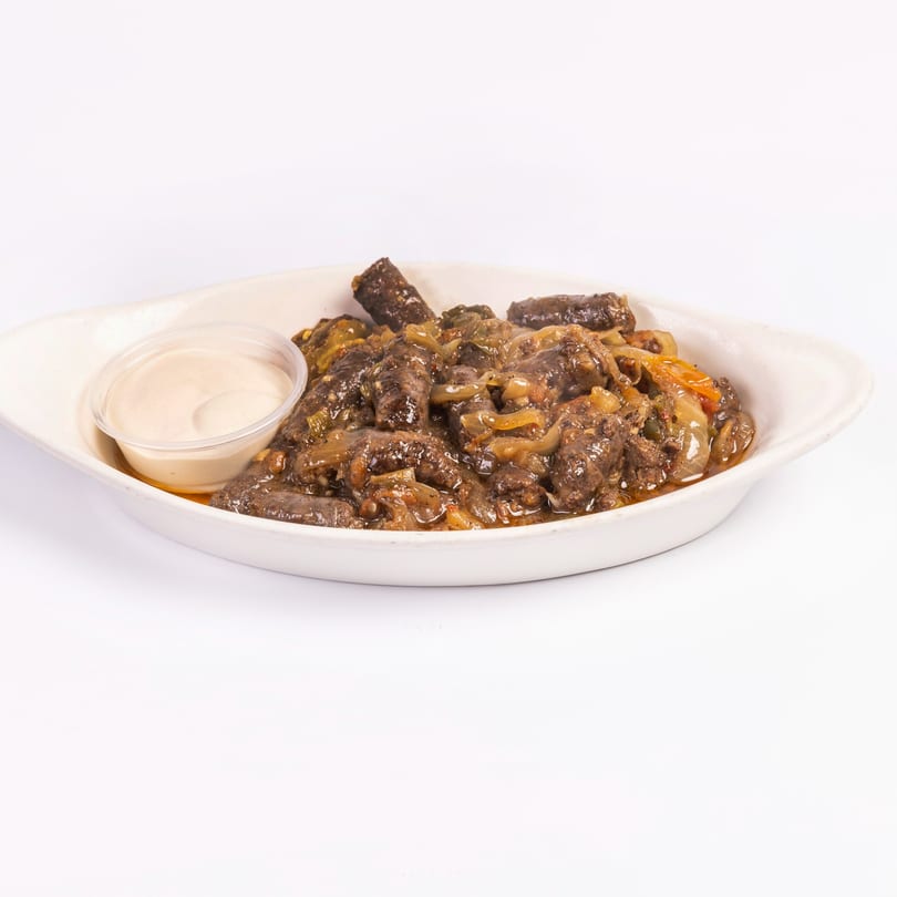 Middle-Eastern sausage dish with onions and sauce in a white serving dish.