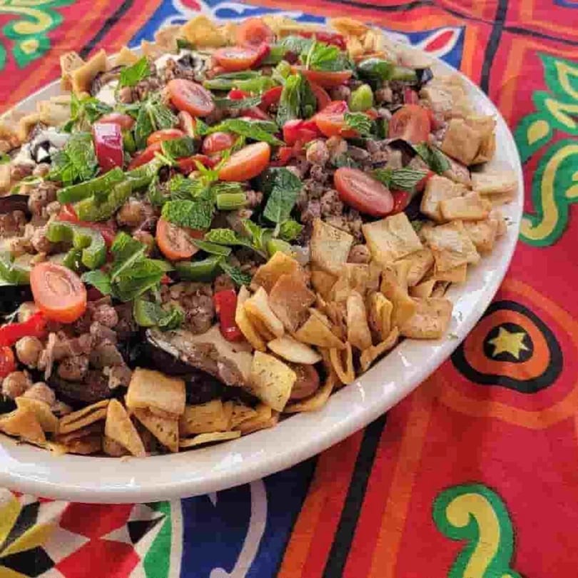 A large platter of Kenz Cairo's Middle Eastern fattah, topped with tomatoes, mint, and crispy bread.